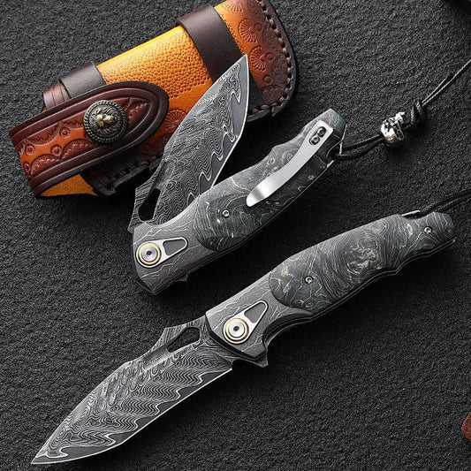 Two folding knives with Damascus steel blades and leather sheaths on a dark surface.